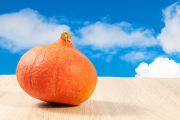 Wall Mural - Hokkaido pumpkin on a wooden table under blue sky 