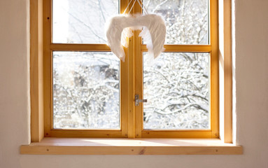 Poster - Winter snow covered trees seen through the window with angel wings christmas decoration.