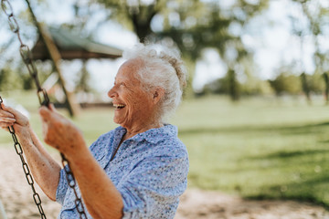 Cheerful senior woman on a swing at a playground