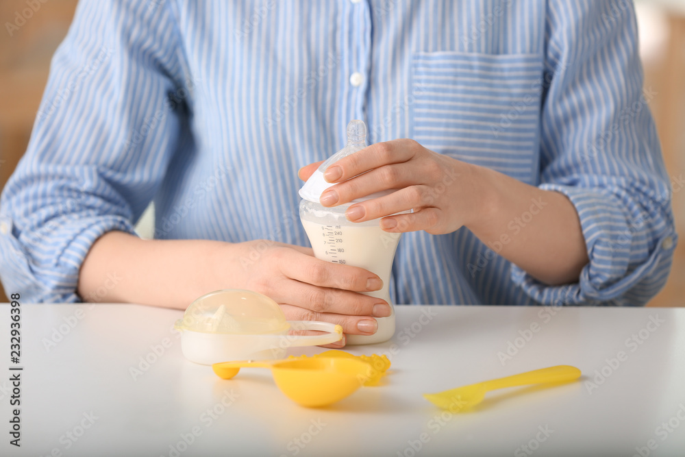 Woman preparing baby formula at table