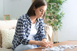 © Pixel-Shot - Young woman doing jigsaw puzzle at home