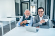 © bnenin - Portrait of a senior business man and younger colleague drinking coffee in the office.