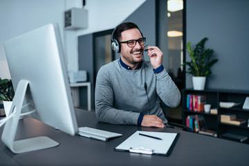 Happy tech support operator in headset consulting a client.