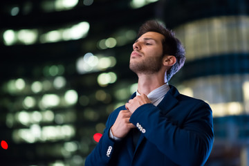 Businessman adjusting his necktie at night