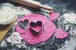 Baking concept for St. Valentines Day with heartshaped cutters and pink cookies on the dark table. Valentines day. Homemade  pink heart cookies.