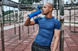 © Friends Stock - Young african man at the open air gym is resting with water