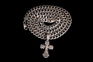 Silver Orthodox cross on a silver chain rolled up in circles