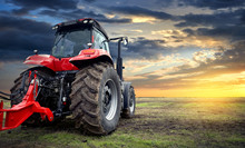 Agricultural Tractor Working In The Field At Sunset Background