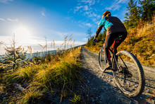 Cycling Woman Riding On Bike In Autumn Mountains Forest Landscape. Woman Cycling MTB Flow Trail Track. Outdoor Sport Activity.