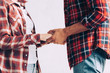 cropped image of couple in checkered shirts holding hands at home
