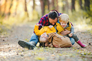 Wall Mural - A mature father with backpack and toddler son in an autumn forest.