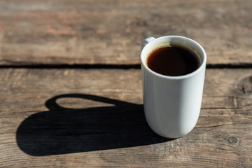 Closeup of a Cup of black coffee on a wooden table outdoors