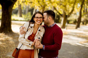 Wall Mural - Young woman and man walking in city park holding hands