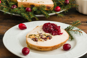 Wall Mural - Stuffed  turkey breast roll with cranberry sauce on white plate on rustic wooden table