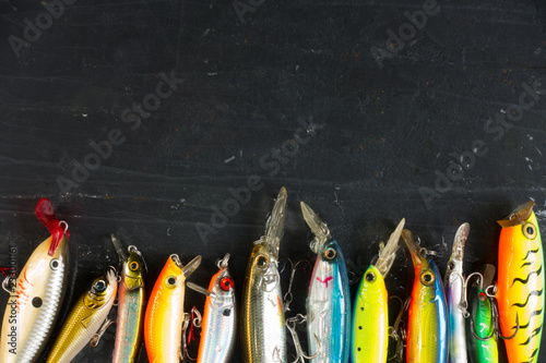 Fotomural Various of fishing lures colorful on black stone wet background.