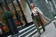 © Friends Stock - Fashion. Young stylish woman walking on the city street looking aside curious