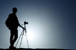 A photographer with tripod with sun and blue sky