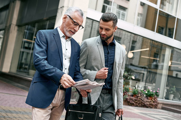 Wall Mural - Two businessmen discussing about the new project while walking outdoors.