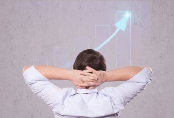 Businessman relaxing on chair, back view, chart on background