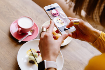 The girl in the restaurant photographing the food on the phone.