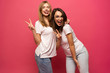 © opolja - Two exited woman having fun and raising hands up. Standing on pink background. Lucky mood.