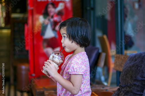 Fotografie, Obraz Portriat Asian little girl drinking blended ice chocolate with funny face
