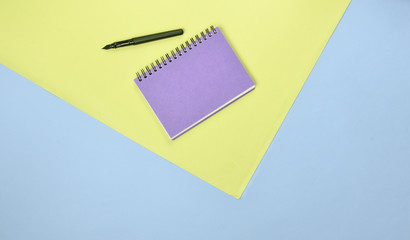 Poster - Notepad and pen on a colored pastel background. Minimalism, top view.