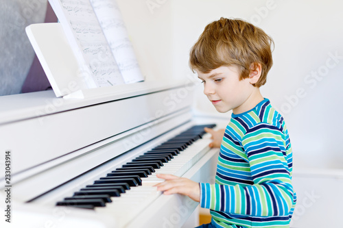 Plakaty pianino  piekny-maly-chlopiec-dziecko-ze-sluchawkami-gra-na-pianinie-w-salonie-lub-szkole-muzycznej-przedszkole