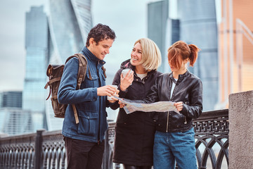 Wall Mural - Group of happy tourists searching place on the map in front of skyscrapers