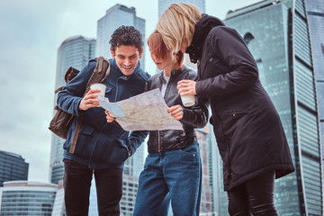 Wall Mural - Group of tourists searching place on the map in front of skyscrapers