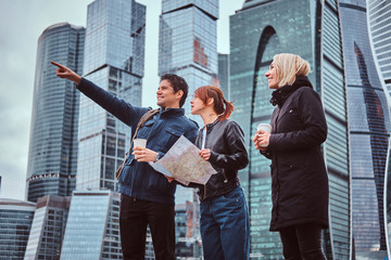 Wall Mural - A handsome man showing the right direction and showplace to female tourists in front of skyscrapers