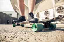 Close-up Of Legs And Longboard Standing On Asphalt
