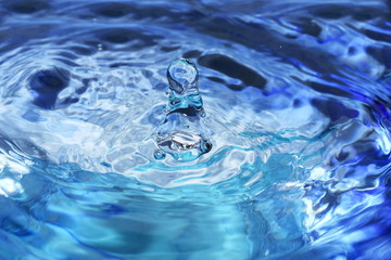 Splash and ripples in blue water liquid