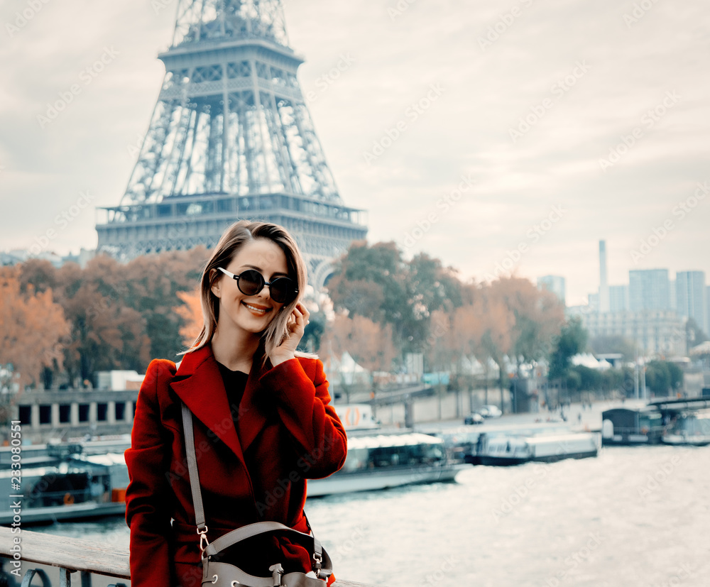 Style redhead girl in red coat make a photo on parisian street in autumn season time. Eiffel tower on background - obrazy, fototapety, plakaty 