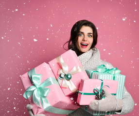 Wall Mural - Joyful woman holding a lot of boxes with gifts on a pink background.