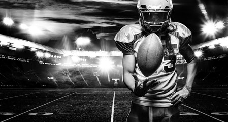 American football player, athlete in helmet with ball on stadium. Black and white photo. Sport wallpaper with copyspace.