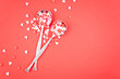 Pair of spoons with sweet hearts-confetti on a red background.