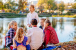 © Iryna - Female paitner artist teaching group of children outdoor on lake shore in autumn summer day. Open air activity for school age children concept.