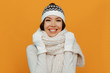 © PinkCoffee Studio - Woman portrait. Accessories. Warmness. Asian girl in a white scarf, cap and gloves is smiling, on an orange background