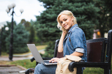 Young blonde girl with a laptop on the streets of the city