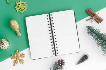 Wall Mural - Creative flat lay of craft and blank notebook mock up with christmas ornaments on green and white background, Top view blank space minimal style.