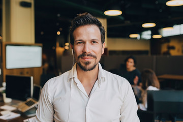 Portrait of confident businessman with earphones in office