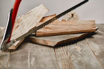 Wall Mural - Close up view of hacksaw and wood logs on wooden table on grey background