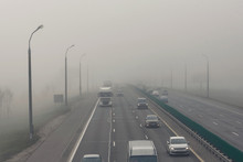 .Dense Fog And Poor Visibility On The Road. Dangerous Driving Situations. View On Highway Traffic In Misty Morning. Low Visibility. Smoke On The Road. Semi-trailer Truck And Cars Driving Trough Haze