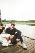 © Maskot - Smiling couple with friends on jetty over lake during weekend getaway