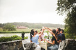 © Maskot - Friends toasting drinks during dinner party in backyard