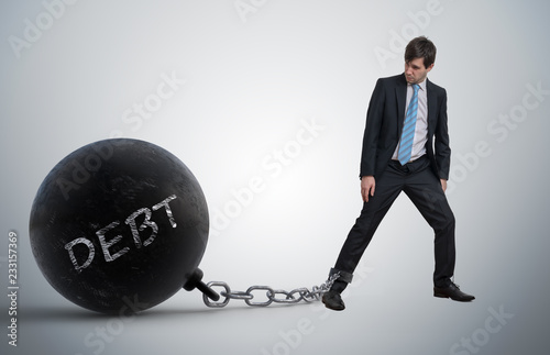 Fotografía Young businessman has chained big metal ball to his leg with deb