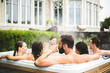 © Maskot - Mid adult man drinking alcohol while enjoying with friends in hot tub during weekend