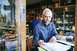 © Maskot - sales clerk reading documents while sitting at table in store