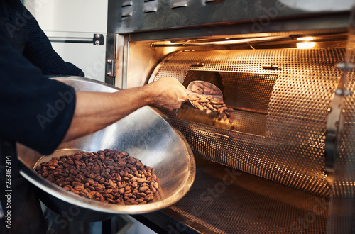 Fotografía Chocolate making factory worker putting cocoa beans into a roaster